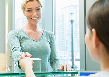 Smiling woman checking in at dental office reception desk