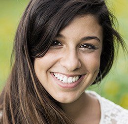 Young woman with brown hair smiling outdoors