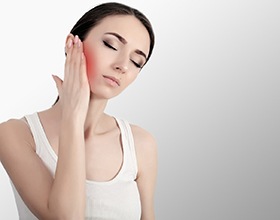 Woman touching the side of her face, experiencing TMJ pain