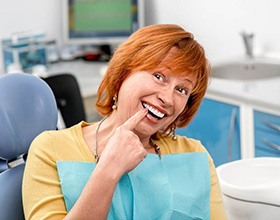 A woman pointing out her new dental implant