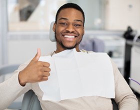 Man in dental chair smiling and giving thumbs up