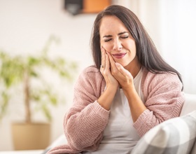 Woman sitting on couch with tooth pain